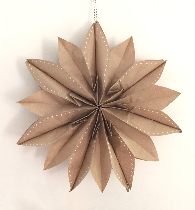 A star decoration made out of paper bags and decorated with hole punches.